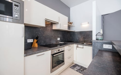 Modern kitchen in Le Central apartment, Millau with cream cabinets, dark granite countertops, and stainless steel appliances