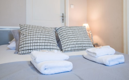 Neatly arranged white towels and checkered pillows on a bed in Le Central apartment, Millau