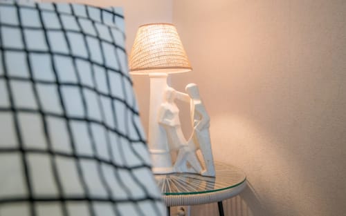 Elegant table lamp with woven shade and sculptural white base in Le Central apartment, Millau
