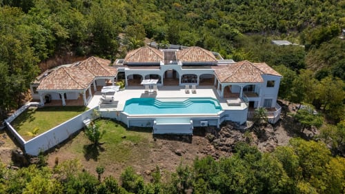 Vue aérienne du resort de luxe Villa Agama à Saint-Martin avec piscine turquoise, toits en terre cuite et végétation tropicale luxuriante