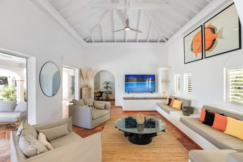 Séjour lumineux et spacieux de Villa Agama avec hauts plafonds, mobilier beige, œuvres côtières et vue océan