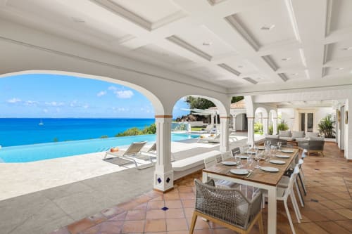 Terrasse de salle à manger en bord de mer de la Villa Agama surplombant les eaux turquoise des Caraïbes à Saint-Martin avec des couverts élégants