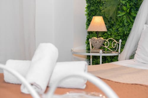 Suite spa moderna all'Elite Apartment SPA di Catania con parete verde, lampada comodino e biancheria bianca