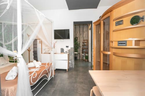 Suite spaziosa di Elite Apartment SPA a Catania con arredamenti in legno, letto a baldacchino, TV e comfort moderni