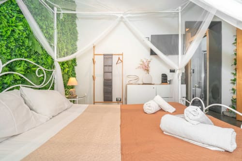 Lussuosa suite spa all'Elite Apartment SPA di Catania con letto a baldacchino, pareti verdi viventi e asciugamani bianchi su tappeto arancione