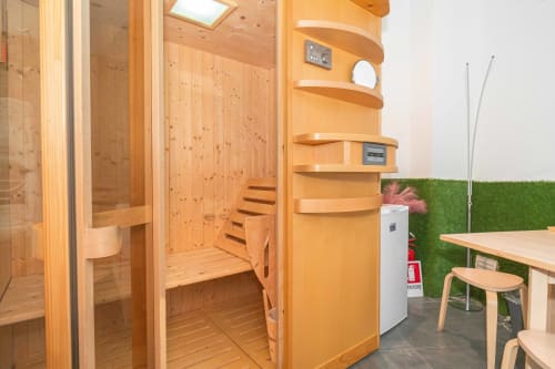 Moderna sauna in legno con scaffali curvi, specchio e comandi nella suite spa dell'Elite Apartment a Catania