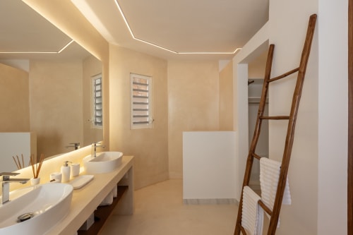 Salle de bain moderne de la Villa Agama à Saint-Martin avec vasques doubles, échelle à serviettes en bois et éclairage chaleureux