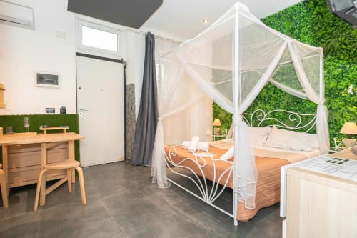 Lussuosa suite con letto a baldacchino bianco, servizi spa e parete verde viva presso Elite Apartment SPA a Catania