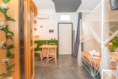 Suite compatta all'Elite Apartment SPA di Catania con arredi in legno, parete verde salvia, letto a baldacchino e