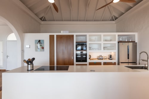 Cuisine moderne avec armoires blanches, accents bois et électroménagers inox à Villa Agama, Saint-Martin
