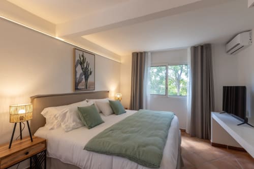Chambre moderne à la Villa Agama à Saint-Martin avec lit queen, accents verts, éclairage ambiant et vue sur le jardin