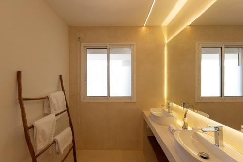 Salle de bains moderne de la Villa Agama à Saint-Martin avec double vasque, éclairage chaleureux et porte-serviettes en bois