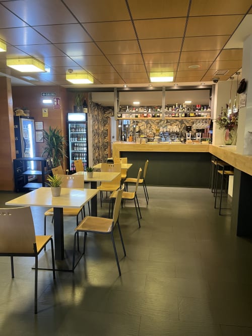 Bar y salón del hotel Casa Azcona en Zizur Mayor con mesas de madera, sillas y mostrador de servicio