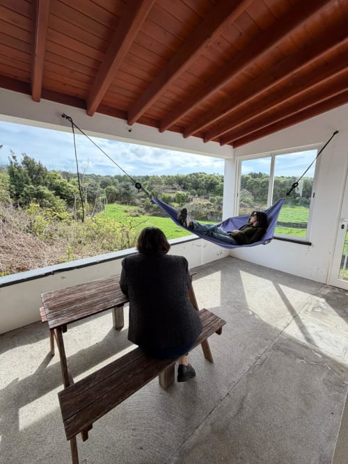 Guest relaxing in hammock on covered patio overlooking green valley at Casa da Avó Alice villa, Inn Nature hotel, São Roque