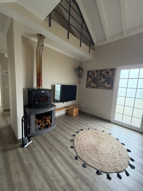 Modern living room in Casa da Avó Alice villa with wood stove, TV, and round jute rug at Inn Nature, São Roque do Pico