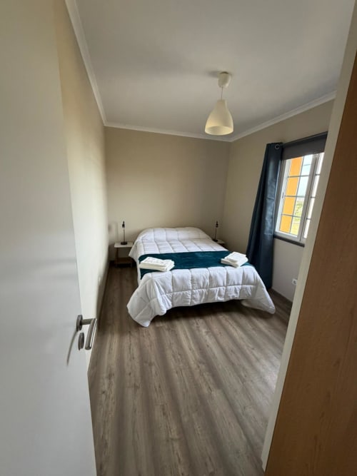 Spacious bedroom at Casa da Avó Alice villa in São Roque do Pico with twin beds, pendant lighting, and city view window