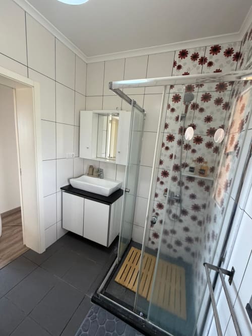 Modern bathroom at Casa da Avó Alice villa in São Roque do Pico with shower, white sink vanity, and floral tiling