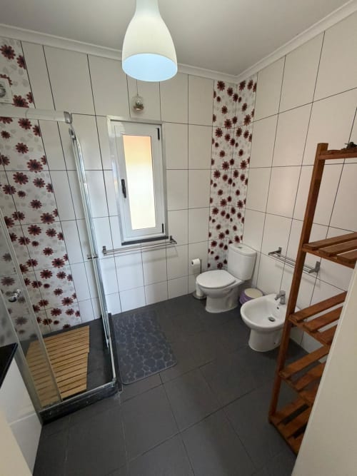 Modern bathroom at Inn Nature villa in São Roque do Pico with white tiles, burgundy accents, shower, toilet, bidet and wooden