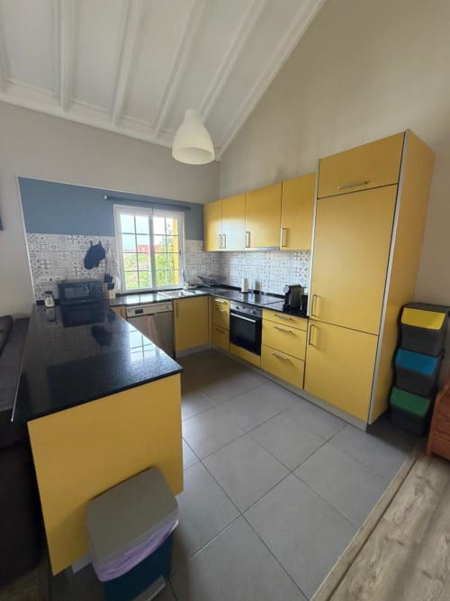 Bright yellow kitchen with black countertops and modern appliances at Casa da Avó Alice villa in São Roque do Pico