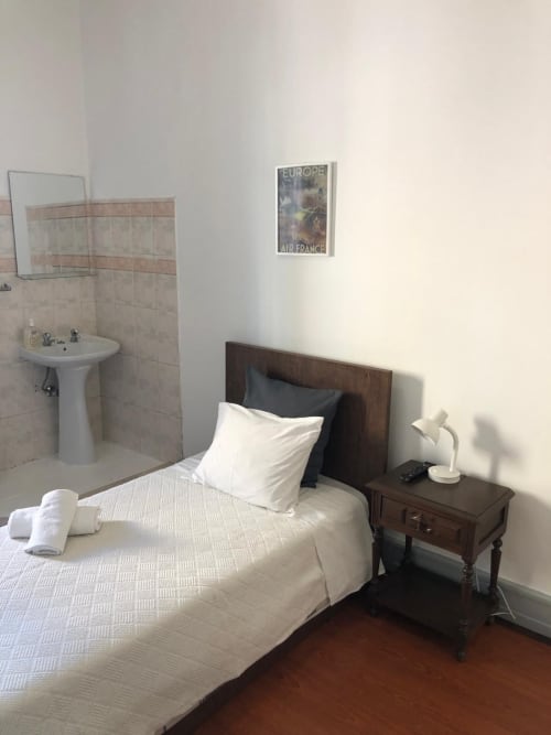 Quarto individual na Guest House Infante Dom Henrique em Coimbra com cama de madeira, roupa de cama branca, casa de banho partilhada e Air France