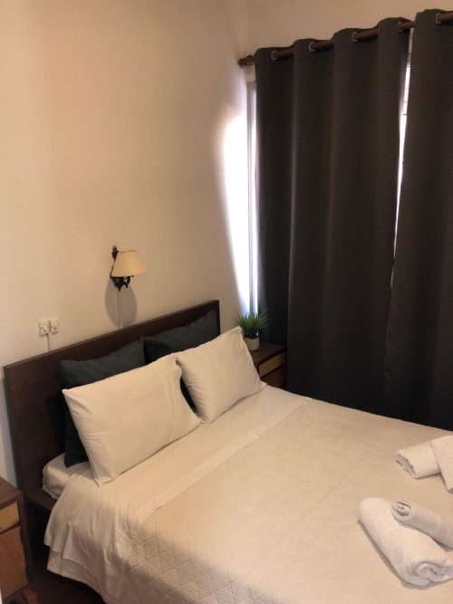 Aconchegante quarto duplo na Guest House Infante Dom Henrique, Coimbra com roupa de cama branca, cortinas escuras e luminária de parede