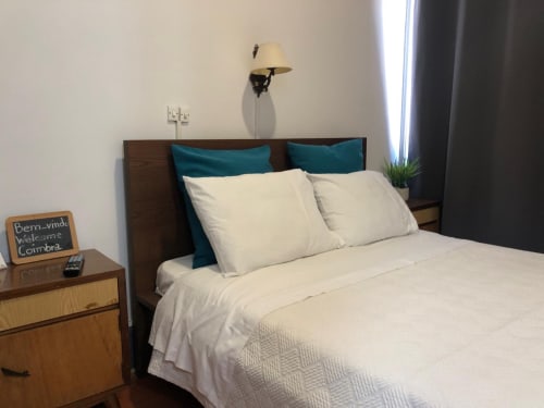 Quarto duplo na Guest House Infante Dom Henrique em Coimbra com roupa de cama creme, almofadas teal, cabeceira de madeira e design moderno