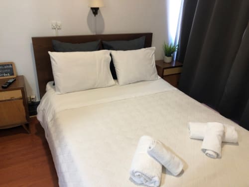Quarto duplo limpo na Guest House Infante Dom Henrique em Coimbra com roupa de cama branca, cabeceira escura e toalhas enroladas