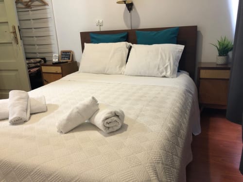 Quarto de hóspedes limpo e aconchegante na Pousada Infante Dom Henrique em Coimbra com toalhas enroladas, cabeceira escura e almofadas teal