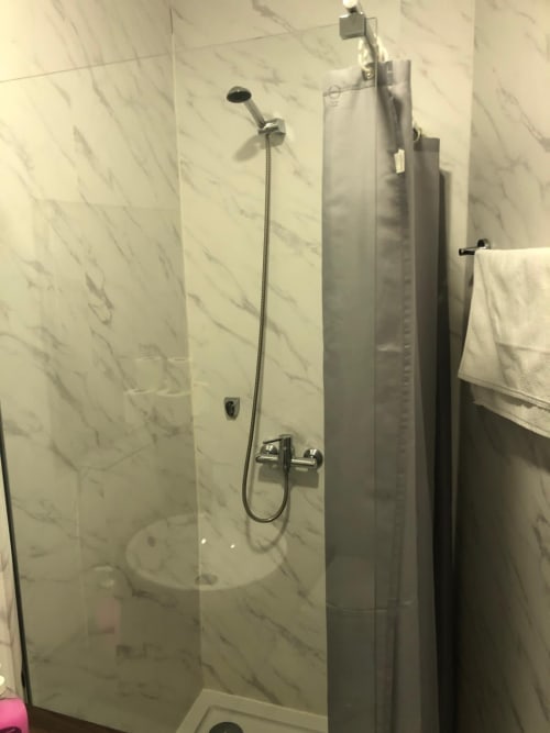 Banheiro moderno com azulejos de mármore e acessórios cromados na Quarto Duplo Deluxe da Guest House Infante Dom Henrique