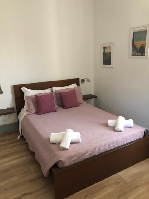 Quarto duplo de luxo com roupa de cama rosa, moldura de madeira escura e arte da Áustria na Guest House Infante Dom Henrique