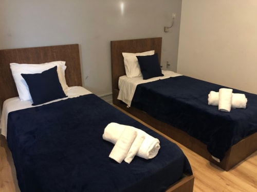 Quarto triplo na Guest House Infante Dom Henrique em Coimbra com duas camas, roupa de cama azul-marinho e toalhas brancas