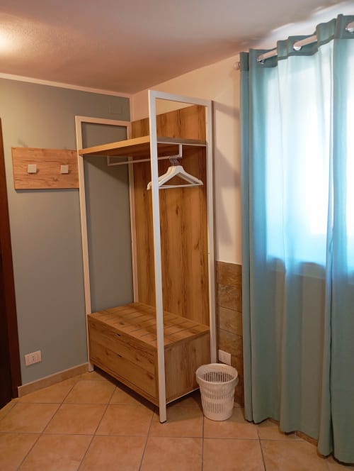 Armadio camera da letto con cornice bianca e porte in legno presso B&B Roccabianca a Stintino, Italia. Pavimento piastrellato con cesto biancheria e