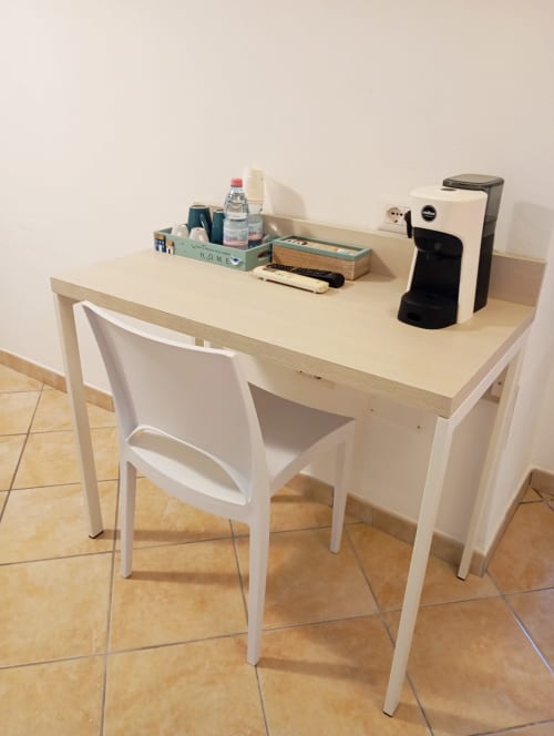 Scrivania in legno chiaro con sedia bianca, macchinetta del caffè e organizer presso le Roccabianca Rooms di Stintino