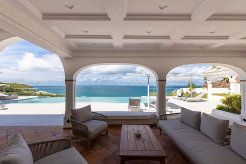 Terrasse couverte de la Villa Agama avec vue sur l'océan, mobilier moderne et piscine à débordement surplombant la côte de Saint-Martin