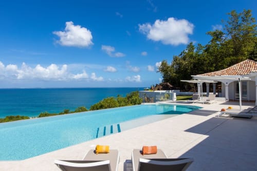 Villa Agama avec piscine donnant sur les eaux turquoise des Caraïbes à Saint-Martin, chaises longues et architecture blanche moderne