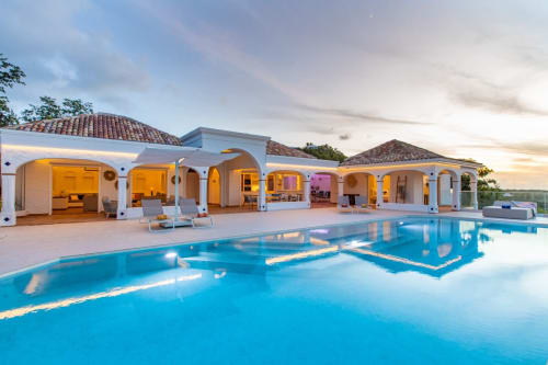 Villégiature de luxe Villa Agama à Saint-Martin avec piscine turquoise, bâtiments aux toits en terre cuite et ambiance crépusculaire