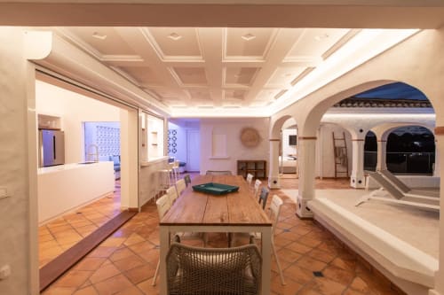 Salle à manger de la Villa Agama avec table en bois, cuisine moderne, portes voûtées et carrelage en terre cuite à Saint-Martin