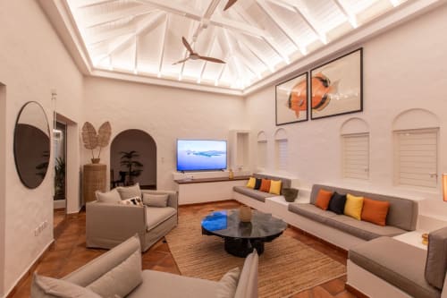 Le salon moderne de la Villa Agama avec canapés crème, plafond avec puits de lumière, table basse noire et décor tropical à Saint-Martin