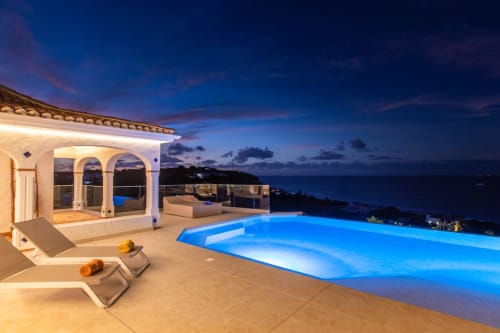 La piscine à débordement illuminée de Villa Agama au crépuscule, avec vue sur la mer des Caraïbes à Saint-Martin