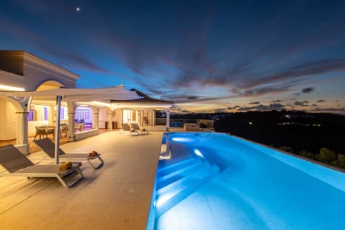 Villa Agama au crépuscule : terrasse piscine illuminée avec piscine à débordement surplombant le paysage de Saint-Martin