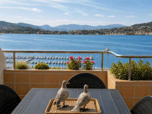 Terraza frente al mar de Baiona con vistas al puerto deportivo, flores en macetas y montañas costeras desde el apartamento Lar de Mar