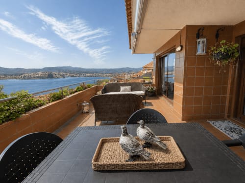 Terraza frente al mar de Baiona con sillas de mimbre frente al océano Atlántico, esculturas decorativas de pájaros sobre la mesa