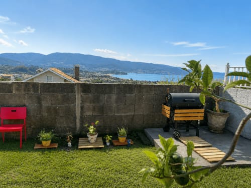 Terraza de casa en entorno rural en Nigrán con vistas al mar, muebles de jardín, plantas en macetas y barbacoa con vista a la bahía