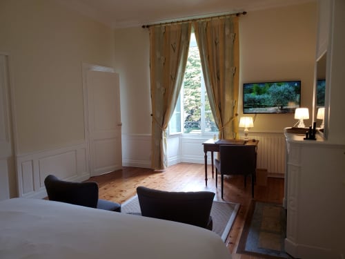 Chambre spacieuse aux Logis des Tourelles à Cognac avec vue sur jardin, bureau, TV et décor français traditionnel