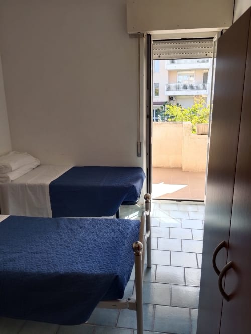 Letti gemelli con coperte blu nell'appartamento Brezza dei Trabocchi di Tales of Abruzzo, Atessa, con balcone sulla vista giardino