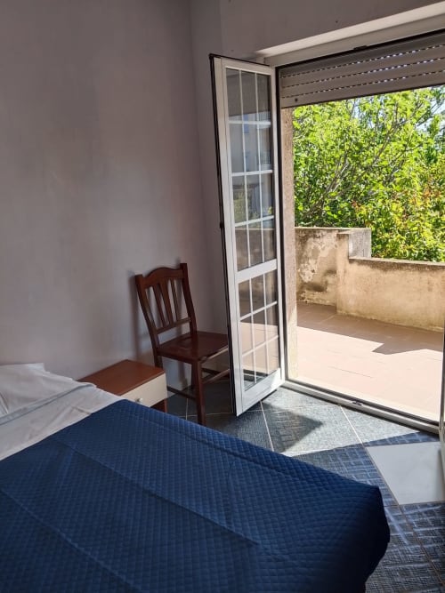Camera da letto con vista mare e balcone a Tales of Abruzzo, Fossacesia. Letto, sedia e porta-finestra che si apre sulla terrazza con giardino