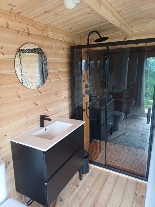 Modern bathroom in Le Grand Chêne at La Maison de Dun B&B, Saint Racho, with black vanity, rainfall shower, and wooden walls