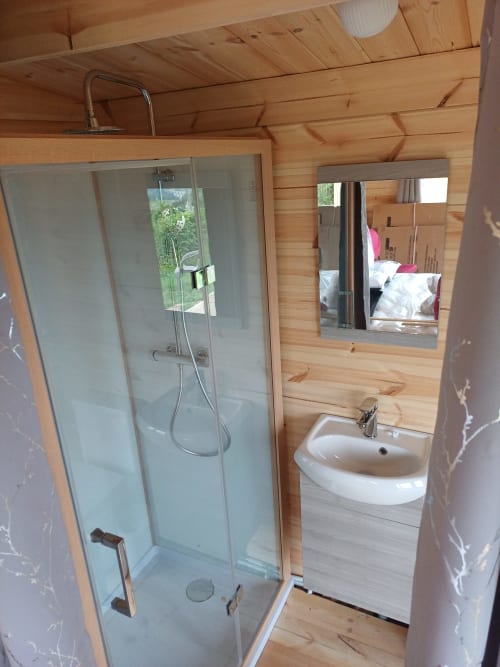 Modern bathroom in Douglas room at La Maison de Dun BnB, Saint Racho, with wooden walls, glass shower, and sink with mirror