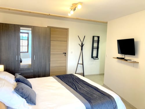 Habitación moderna en Au Château De Villelongue con cama, TV de pared, armario de madera oscura y vistas al jardín