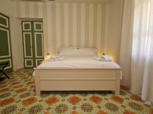 Spaziosa camera con letto bianco, carta da parati a righe, porte verdi e pavimento decorato presso la pensione Il 900 ad Avezzano, Italia